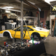 A highly modified yellow Ferrari in a messy shop.